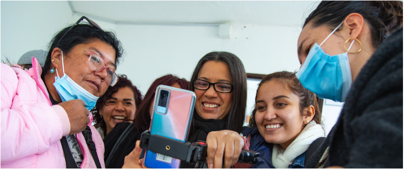 Mujeres sonriendo con un celular