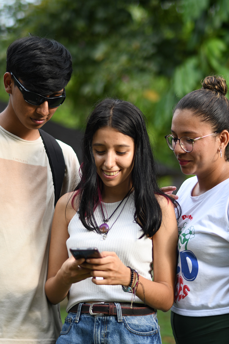 Tres jóvenes suando un dispositivo móvil Tres jóvenes suando un dispositivo móvil