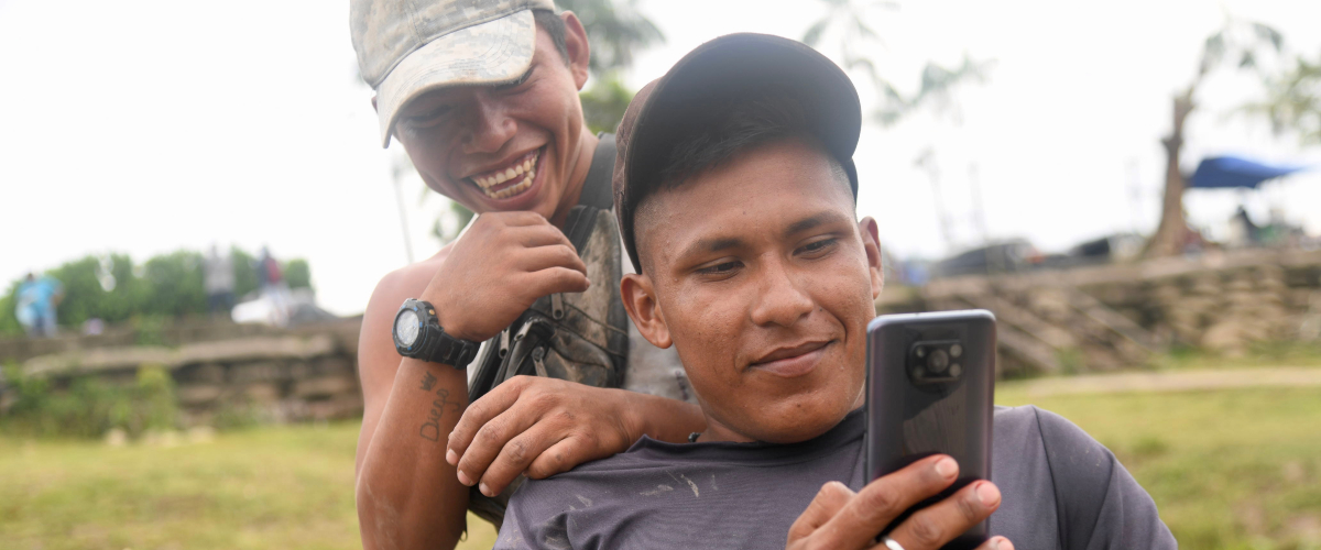Foto de un hombre y mujer abrazados utilizando un celular.