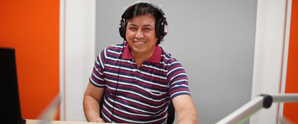 Foto de señor sonriendo con unos audífonos de radio puestos