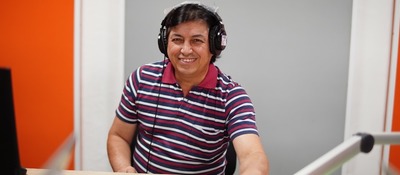 Foto de señor sonriendo con unos audífonos de radio puestos