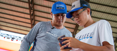 Foto de un joven y un adulto observando un celular