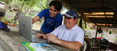 Foto de un joven y un adulto observando un computador