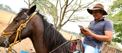 Foto de campesino montando a caballo y consultando su celular