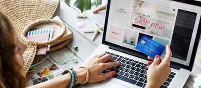 Imagen diseñada con las manos de una persona sosteniendo una tarjeta bancario mientras hace compras virtuales