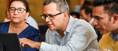 Foto de 3 adultos observando un computador Foto de 3 adultos observando un computador