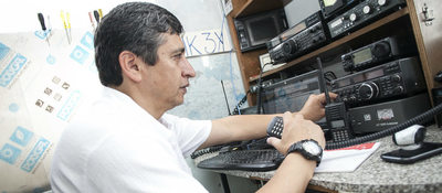Foto de un ciudadano radioaficionado frente a equipos de comunicaciones