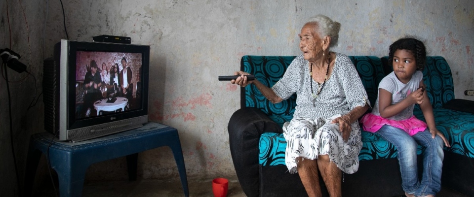 Foto de un adulto mayor y una niña viendo TV