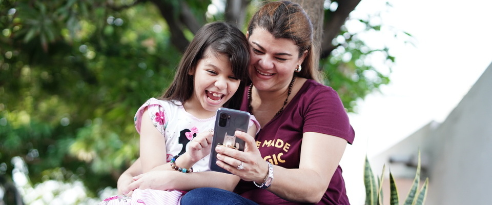Foto de madre e hija consultando un móvil