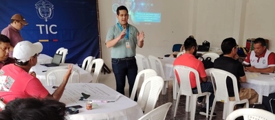 En un salón comunitario en Mitú, un facilitador expone frente a varias mesas donde participantes dialogan y escriben ideas para el CONPES de Educación Digital.