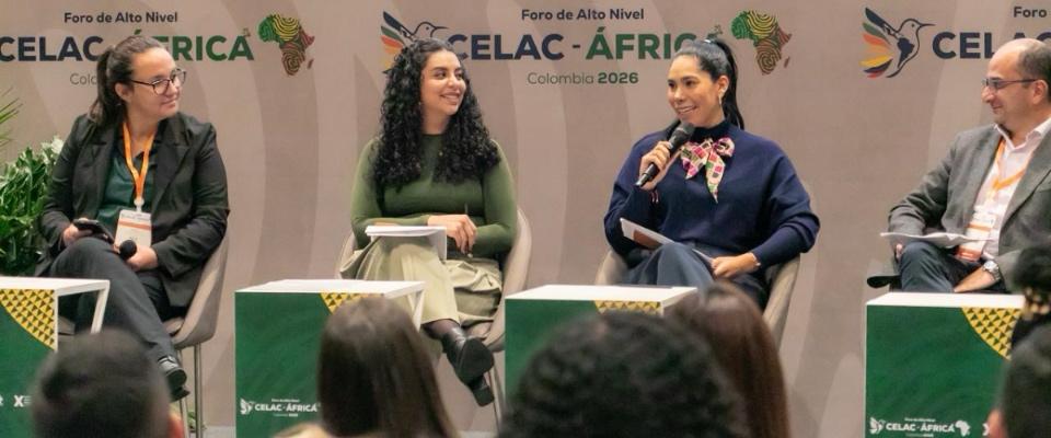 Panel con cuatro personas en escenario del Foro CELAC–África en Colombia; una mujer habla con micrófono mientras dialogan sobre equidad digital