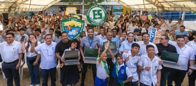Multitud de estudiantes y docentes sonríen bajo carpa, algunos levantan portátiles; celebran entrega de tecnología en comunidades del Cesar.