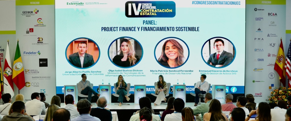 Panel de expertos en escenario con pantalla grande; público atento escucha debate sobre contratación pública y tecnología del Ministerio TIC.