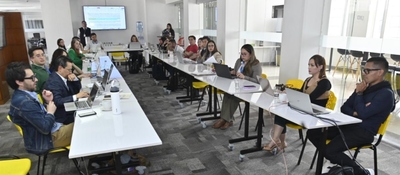 Personas en sala moderna trabajan con portátiles en mesas largas. Avanza reglamentación de Entornos Digitales Sanos con apoyo pedagógico.