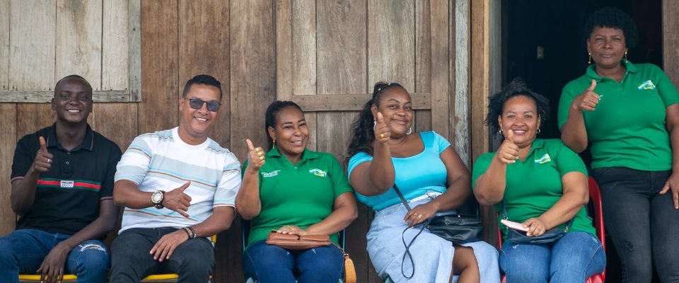 Foto de dos hombres y cuatro mujeres afroamericanos sonriendo y sosteniendo sus manos con el pulgar arriba