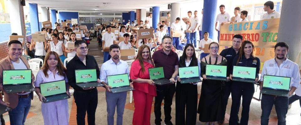 Entrega de computadores en Santander: grupo de funcionarios sostiene portátiles frente a estudiantes con cajas en jornada educativa.