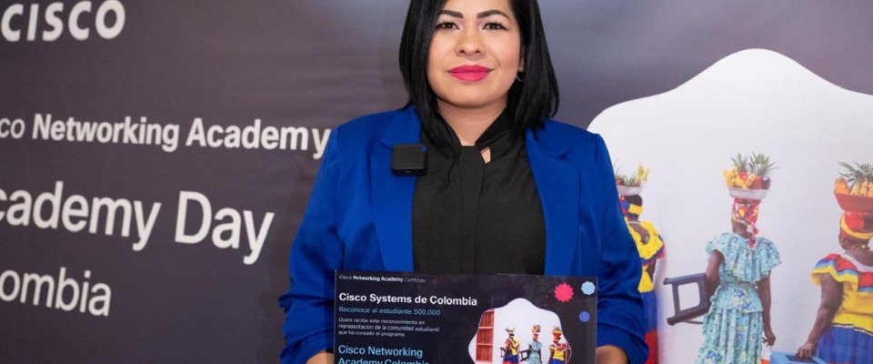 Mujer con blazer azul sostiene reconocimiento de Cisco en Academy Day Colombia 2026, destacando formación de talento con AvanzaTEC.