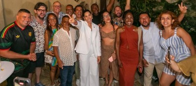 Grupo de personas sonríe y posa unido en un evento nocturno; visten atuendos elegantes y casuales, celebrando logros de la televisión pública.