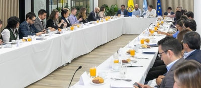 Personas en mesa larga de reunión con jugo y café, dialogan sobre estrategia conjunta para impulsar la transformación digital inclusiva en Colombia