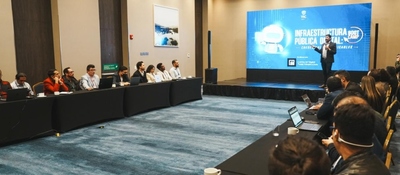 Salón de conferencia: asistentes con portátiles escuchan a un expositor frente a pantalla sobre trámites digitales del Estado.