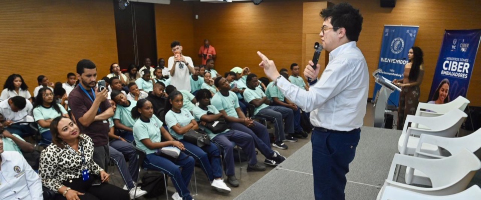 Conferencista habla con micrófono ante jóvenes uniformados en auditorio; evento educativo sobre ciudadanía digital en San Andrés
