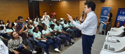 Conferencista habla con micrófono ante jóvenes uniformados en auditorio; evento educativo sobre ciudadanía digital en San Andrés