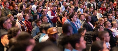 Auditorio lleno de asistentes atentos a una conferencia sobre Bitcoin y economía digital, con público diverso observando el escenario.