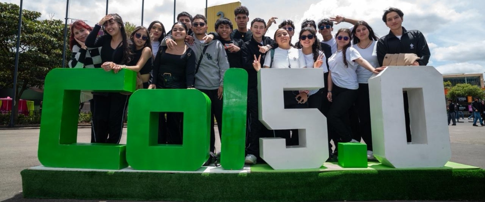 Grupo de jóvenes posa junto al letrero Colombia 5.0 durante evento tecnológico que reunió miles de visitantes.
