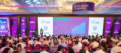 Auditorio lleno durante evento tecnológico con pantallas gigantes y asistentes atentos a charla sobre transformación digital