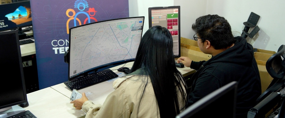 Dos personas monitorean mapas y datos en computadores para coordinar atención de emergencias en zonas apartadas. Dos personas monitorean mapas y datos en computadores para coordinar atención de emergencias en zonas apartadas.