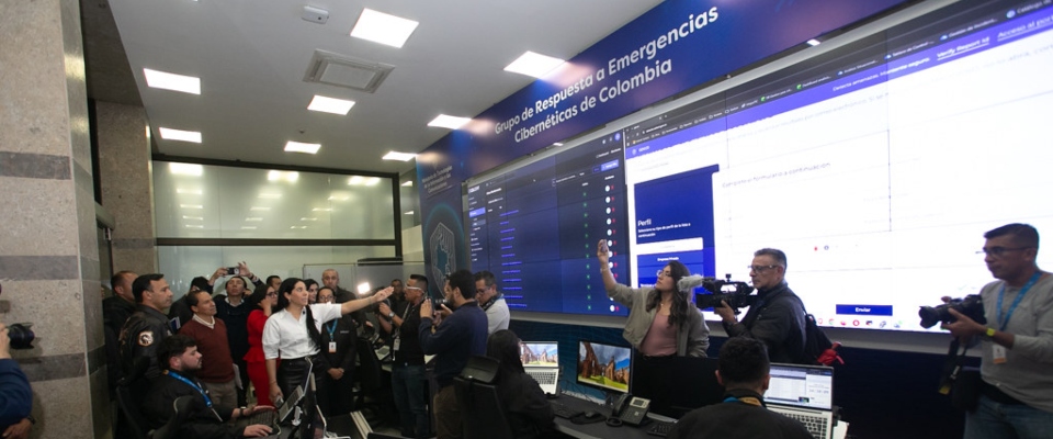 Funcionarios y periodistas observan un centro de monitoreo cibernético durante la coordinación de acciones electorales.