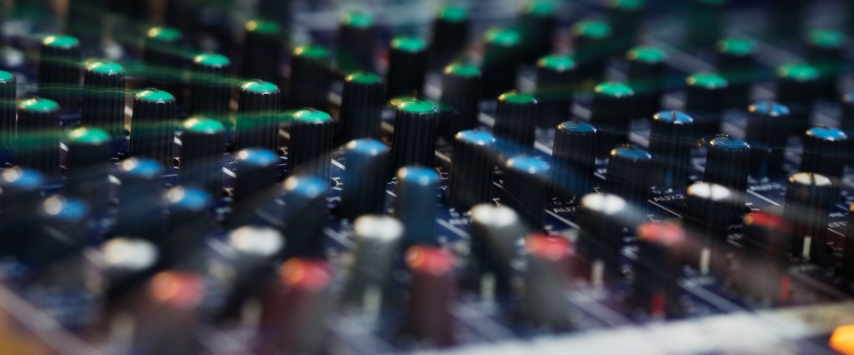 Primer plano de una consola de audio con perillas y controles, símbolo de las comunicaciones y la operación de radioaficionados.