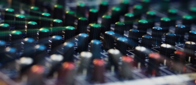 Primer plano de una consola de audio con perillas y controles, símbolo de las comunicaciones y la operación de radioaficionados.