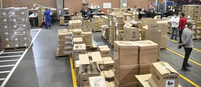 Vista aérea de un centro logístico con estanterías repletas de cajas, montacargas y personal organizando envíos