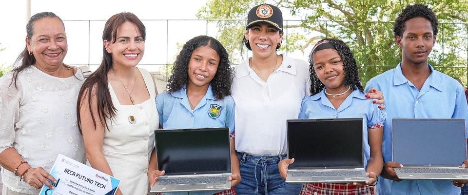 Seis personas posan al aire libre; tres estudiantes sostienen portátiles abiertos. Una mujer sostiene un certificado.