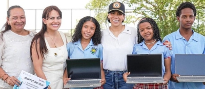 Seis personas posan al aire libre; tres estudiantes sostienen portátiles abiertos. Una mujer sostiene un certificado.