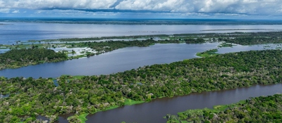 Vista aérea de ríos y lagunas rodeados de vegetación verde; al fondo se observan agua y nubes.