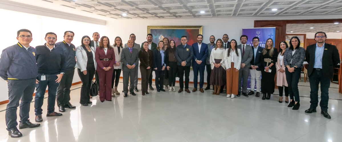 Grupo de personas posa de pie en un salón; al fondo hay un cuadro, una pancarta y mobiliario. Grupo de personas posa de pie en un salón; al fondo hay un cuadro, una pancarta y mobiliario.