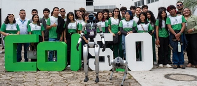 Grupo de personas posa detrás de un robot humanoide y un perro robot, junto a letras grandes verdes y blancas.